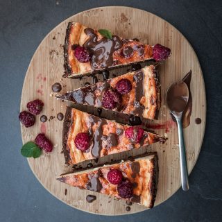 Saftiger Käsekuchen mit einem Brownie Boden, getoppt mit Schokolade und Himbeeren. Brownie-Käsekuchen Rezept auf Purple Avocado.