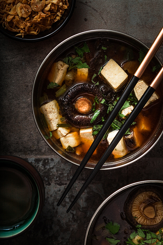 Miso Suppe in einer Schüssel mit Tofu, Pilzen, Kräutern und einem Paar Essstäbchen