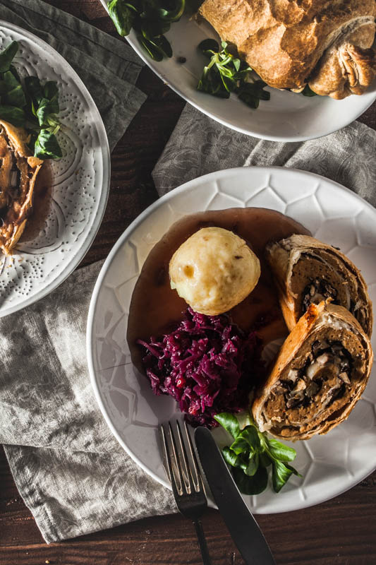 Stuffed seitan in puff pastry served on a plate with cabbage and dumplings