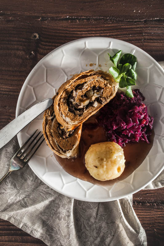 2 slices of vegan seitan roast on a plate served with dumplings and red cabbage