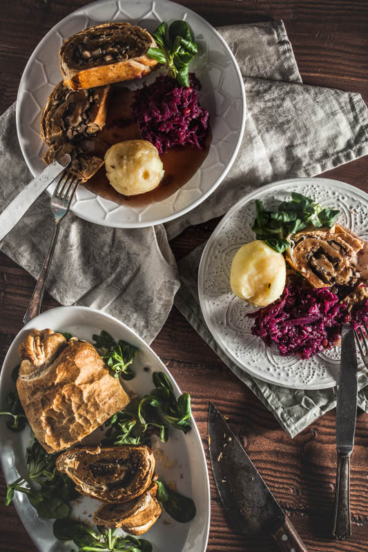 Veganer Braten serviert auf 2 Tellern mit Knödeln, Rotkohl und brauner Sauce