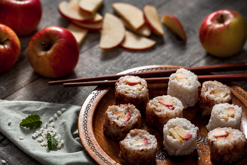 Milchreis Sushi mit Apfel und Vanillesauce. Warum nicht mal süßes Sushi statt der deftigen Variante? Diese süße Sushivariante mit Kokos-Milchreis, Äpfeln und ganz viel Zimt kann man sowohl warm als auch kalt genießen. Foodstyling und Rezept von Purple Avocado