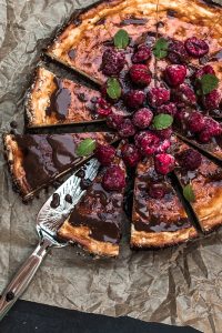 Saftiger Käsekuchen mit einem Brownie Boden, getoppt mit Schokolade und Himbeeren. Brownie-Käsekuchen Rezept auf Purple Avocado.