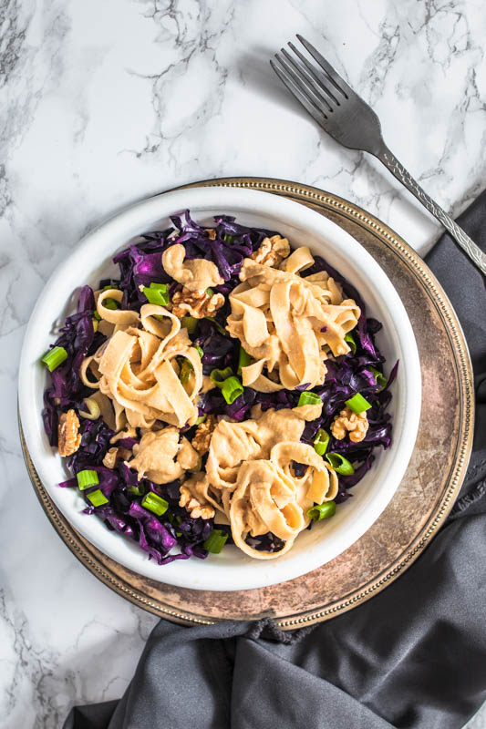 Cremige Hummus Nudeln mit Rotkohl und Walnüssen. Aus Kichererbsen und Sesampaste machen wir eine kräftige Hummus-Sauce für vegane Fettuccine. Schmeckt auch herrlich am zweiten Tag als Salat - perfekt für unterwegs. Rezept und Foodstyling von Purple Avocado.