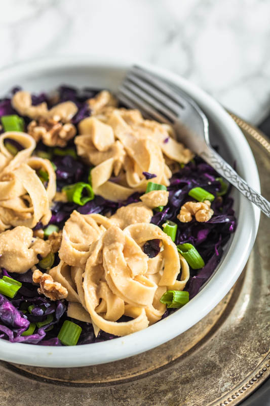 Cremige Hummus Nudeln mit Rotkohl und Walnüssen. Aus Kichererbsen und Sesampaste machen wir eine kräftige Hummus-Sauce für vegane Fettuccine. Schmeckt auch herrlich am zweiten Tag als Salat - perfekt für unterwegs. Rezept und Foodstyling von Purple Avocado.