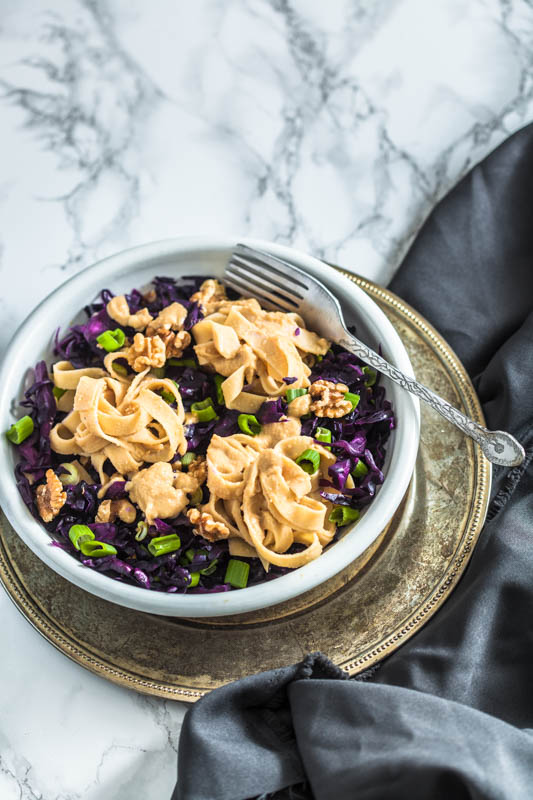 Cremige Hummus Nudeln mit Rotkohl und Walnüssen. Aus Kichererbsen und Sesampaste machen wir eine kräftige Hummus-Sauce für vegane Fettuccine. Schmeckt auch herrlich am zweiten Tag als Salat - perfekt für unterwegs. Rezept und Foodstyling von Purple Avocado.