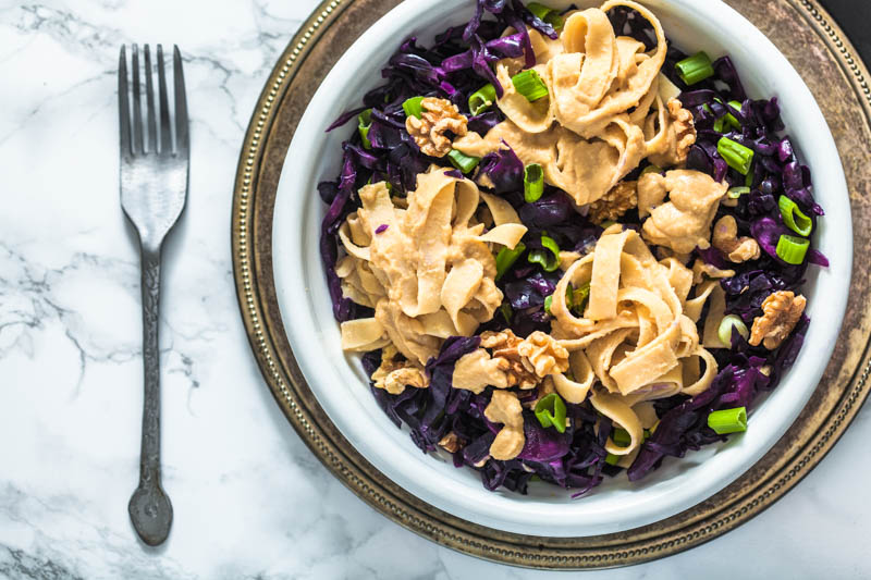 Fettuccine in a creamy hummus sauce with crisp red cabbage and roasted walnuts. Enjoyable warm and cold - perfect salad for to go. Recipe and foodstyling by purple avocado