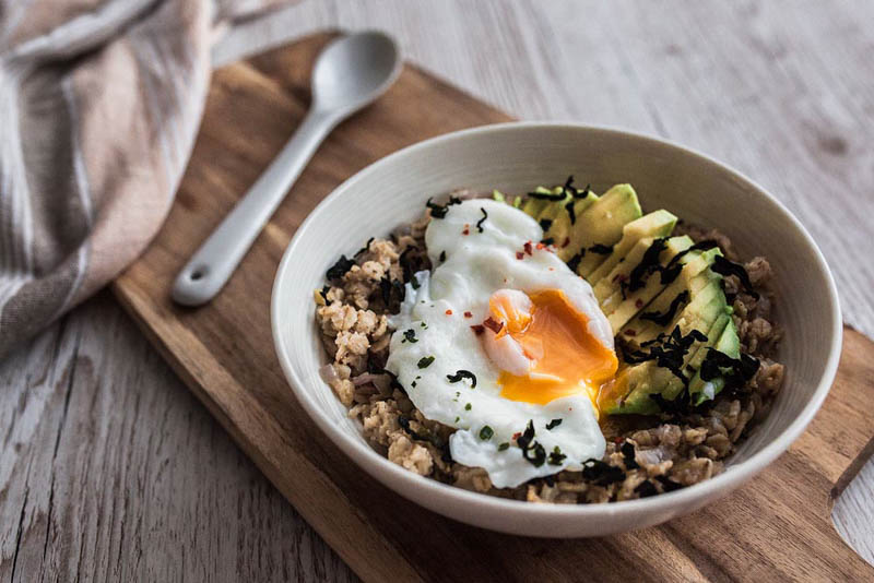 Breakfast becomes dinner with this savoury porridge with avocado, poached egg and roasted sea weed. Recipe and food styling from purple avocado / sabrina dietz.