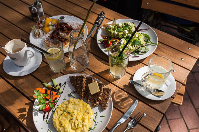 Full breakfast table with scrambled egg, pancakes and avocado baguette in Hamburg at Von der Motte