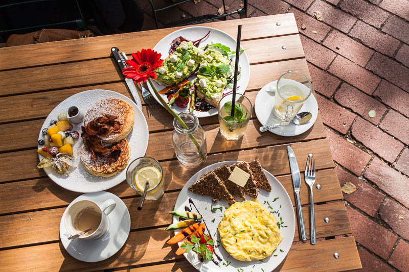 Full breakfast table with pancakes, scrambled egg and avocado baguette in Hamburg at Von der Motte