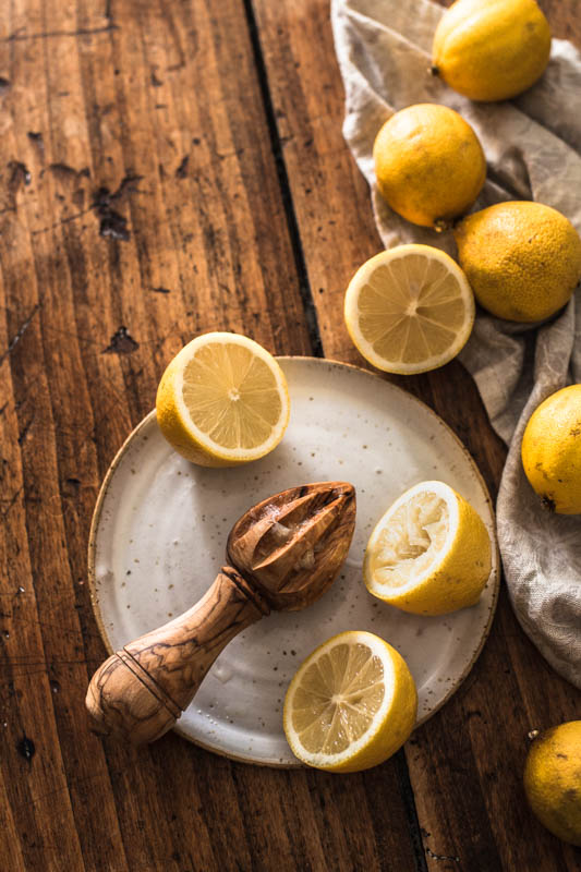 Still life of lemons and a lemon juicer on a rustic wooden counter top