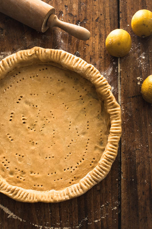 The short pastry dough is put into a cake form and pricked with a fork to prevent it from rising up while baking