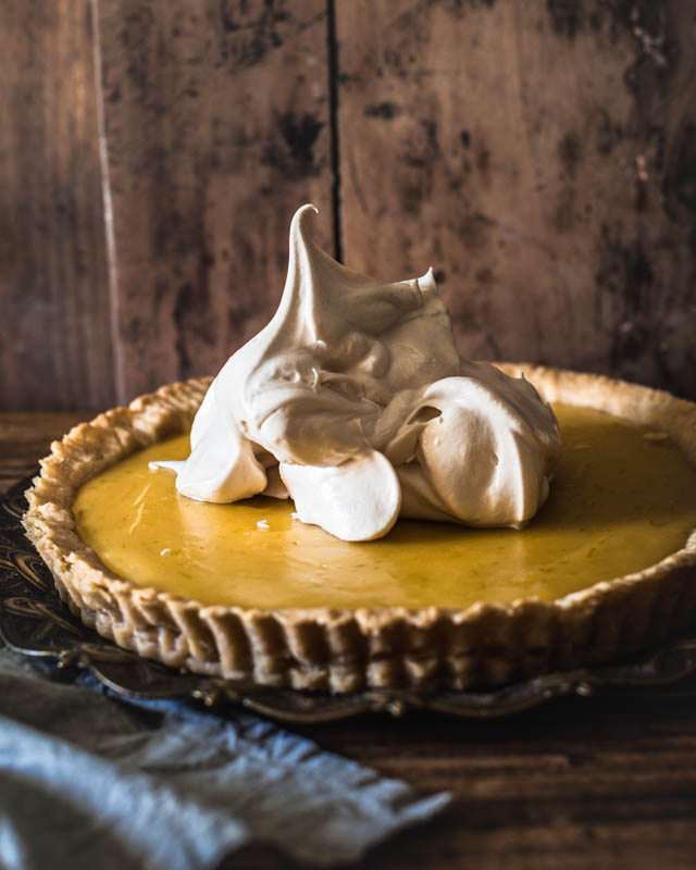 A big scoop of meringue dropped on the cooled down lemon pie. The meringue looks very stiff and fluffy.