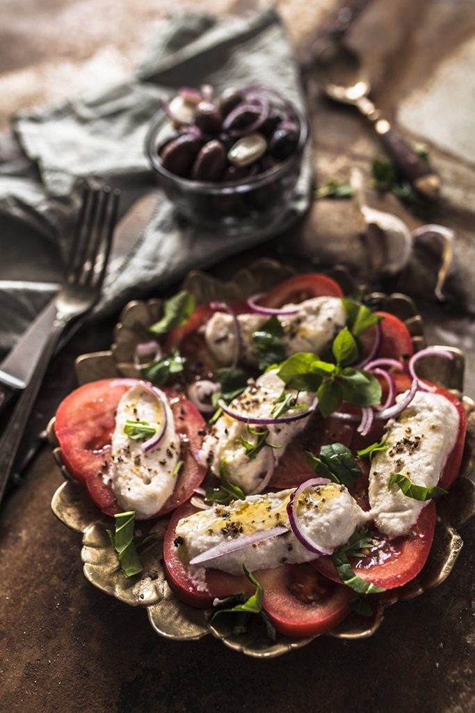 Tomato and vegan Mozzarella served on a golden Plate in a rustic, earthy setting. This photo is used for a thorough photo analysis