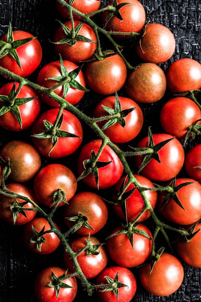 Makrofotografie von Cherrytomaten auf einem verbrannten, schwarzen Untergrund aufgenommen mit einem 50mm von Canon. Die besten Objektive für Food Fotografie