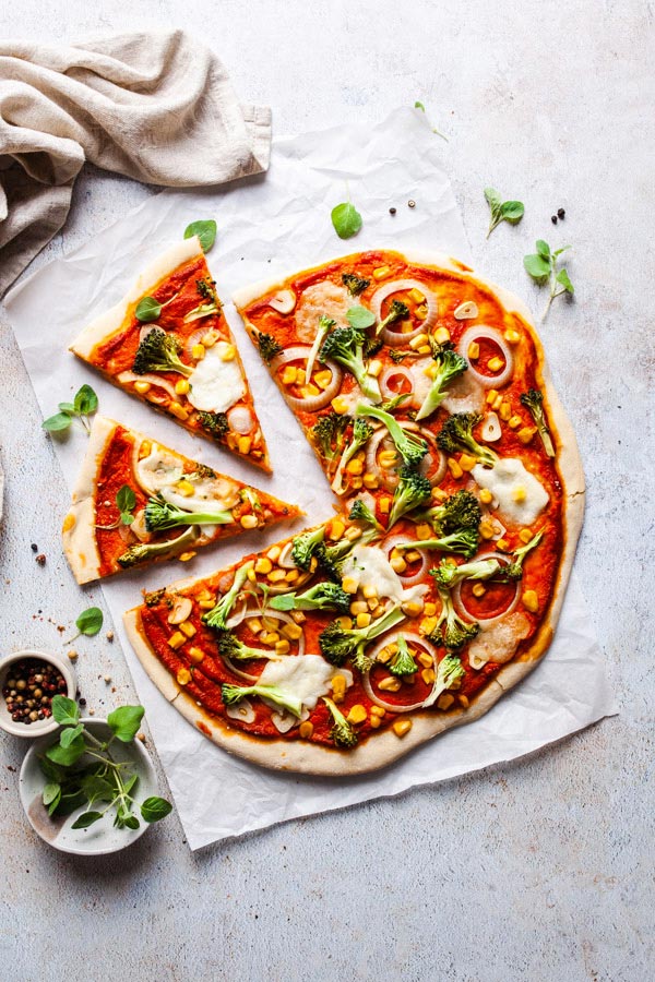 Pizza mit Brokkoli, Mai und Zwiebeln auf einem hellen, texturierten Fotountergrund von PA Backdrops